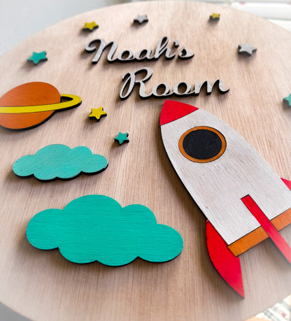 Nursery wall decoration featuring a cute rocket, saturn, stars and clouds shown in close detail